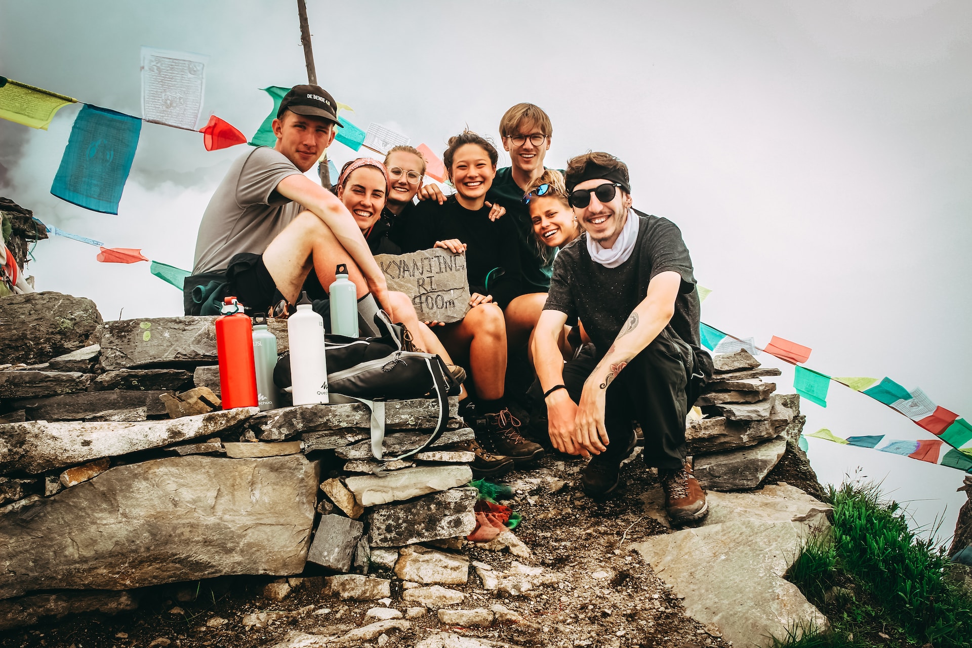 Group of happy hikers friends resting at the top of a mountain smiling for the photo.